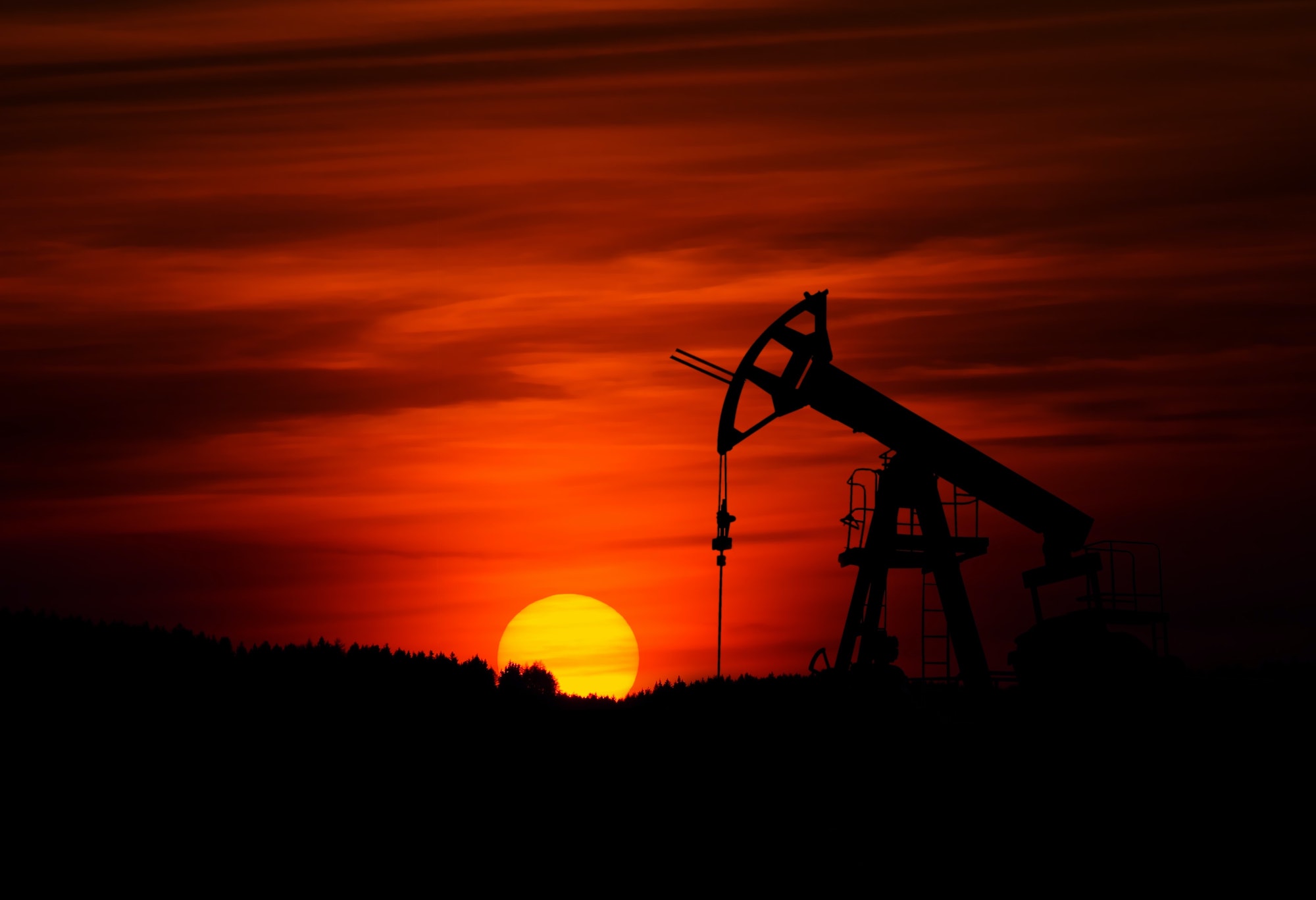 An oil rig with a setting sun in the background