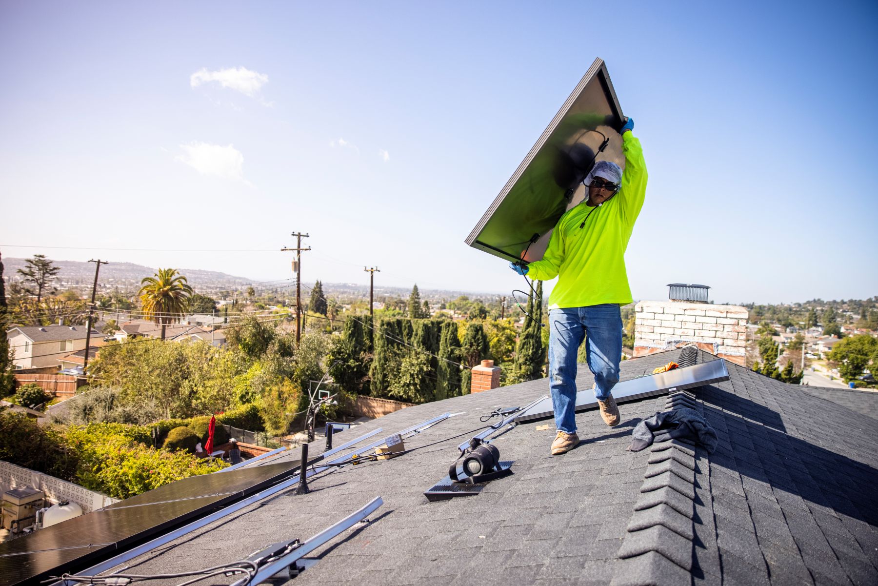 Worker carrying a solar panel on a rooftop 