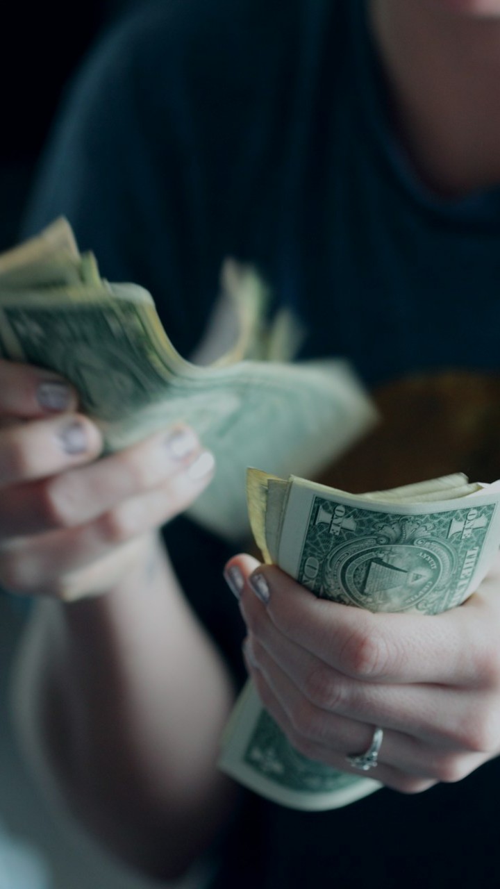 Close up of a person's hands counting dollar bills